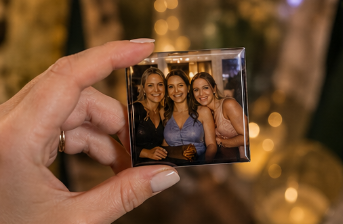 Hand holding a photo magnet of three women